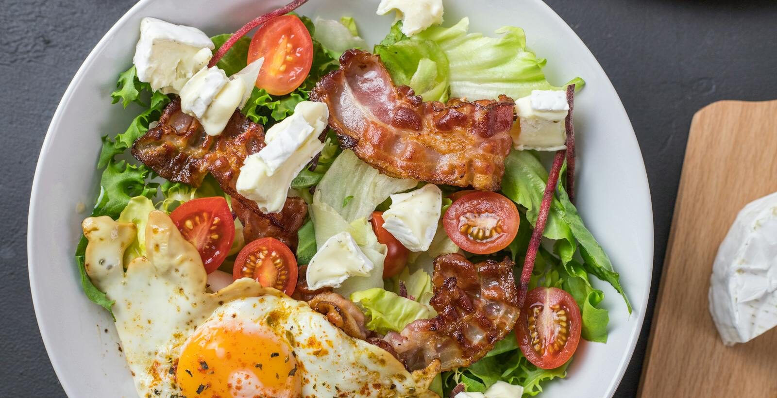 Fresh ketogenic salad with bacon, egg, feta, and tomatoes, perfect for healthy eating.