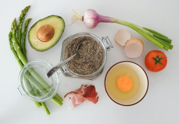Flat lay of fresh asparagus, avocado, egg, tomato, and more for a keto-friendly dish.